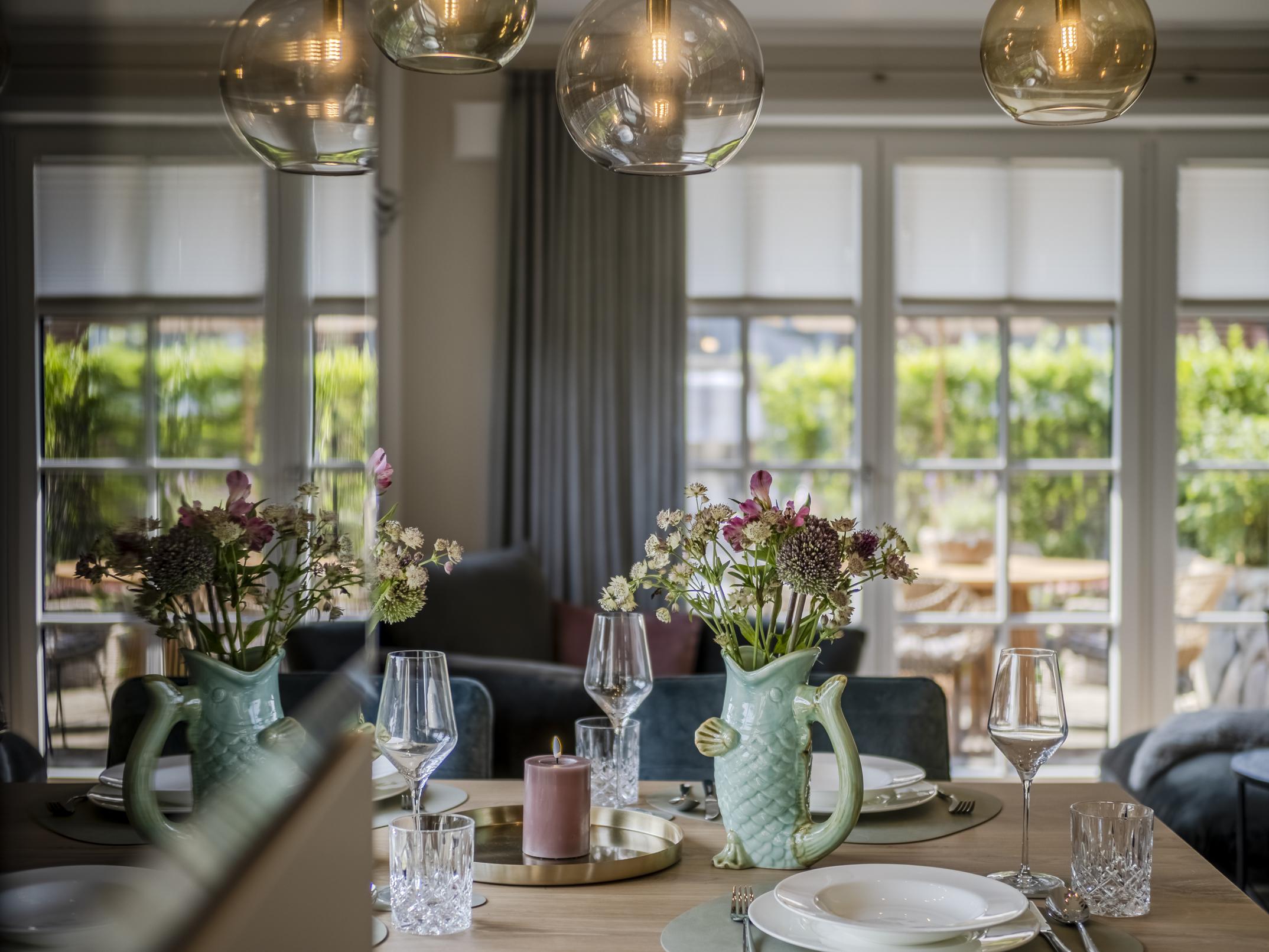 Detailansicht des Esstischs mit stilvoller Dekoration und Blick zur Terrasse.