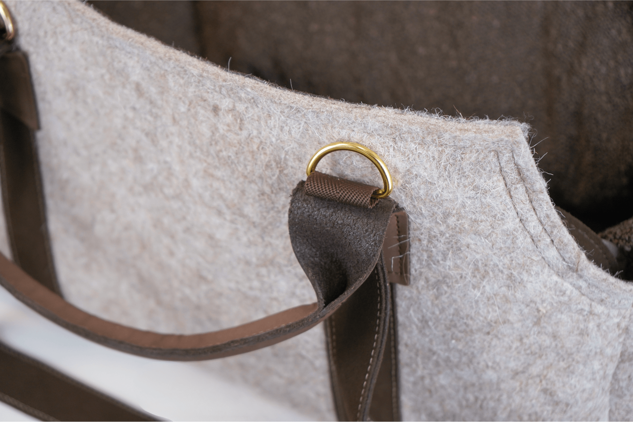 Detailaufnahme der Greta's Luxus-Lodentasche: Ledergriff mit goldfarbenem Messingring am hellen Lodenstoff