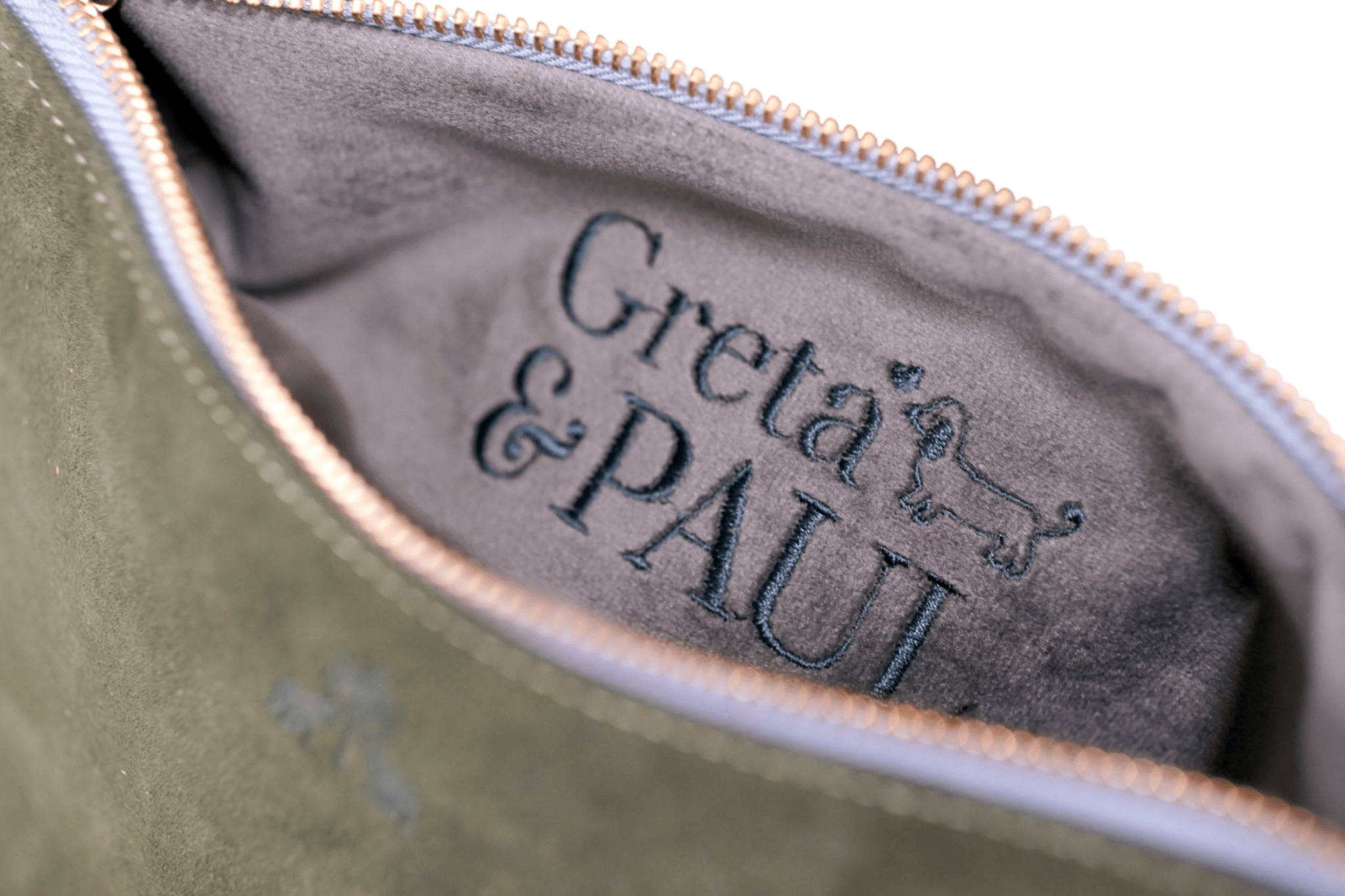 Detailaufnahme des anthrazitfarbenen Innenfutters der Khaki Greta & PAUL Clutch 'Stella Deluxe' mit aufwendig gesticktem Logo