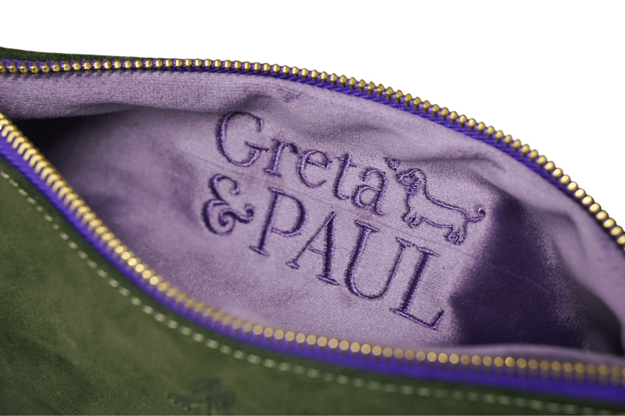 Detailaufnahme des lilafarbenen Innenfutters der Khaki Greta & PAUL Clutch 'Stella Deluxe' mit aufwendig gesticktem Logo