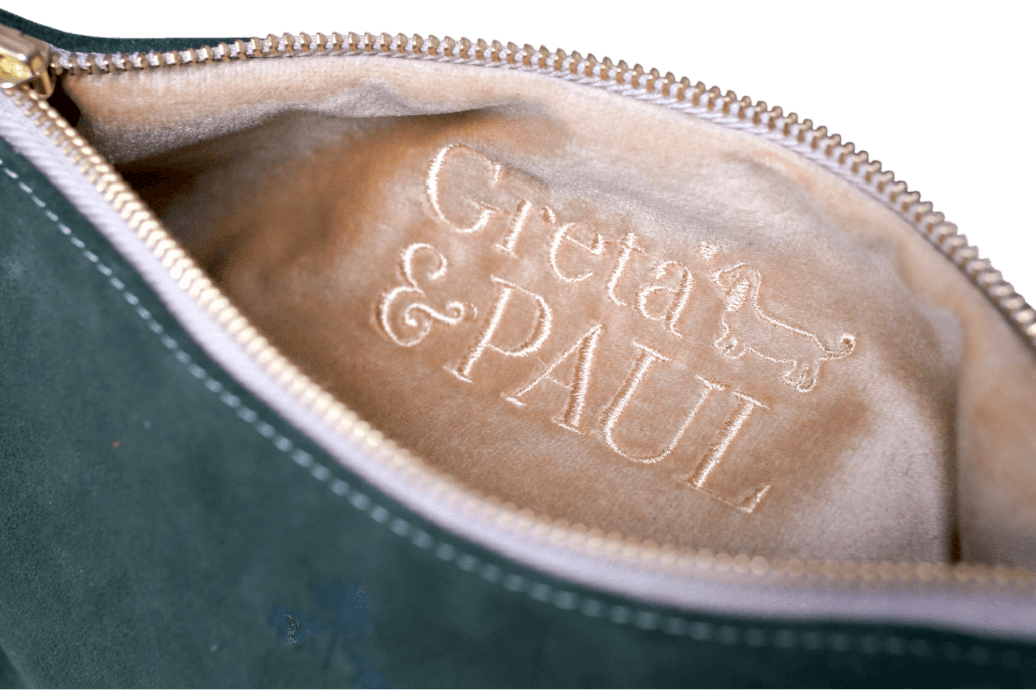 Detailaufnahme des gold-beigen Innenfutters der Khaki Greta & PAUL Clutch 'Stella Deluxe' mit aufwendig gesticktem Logo