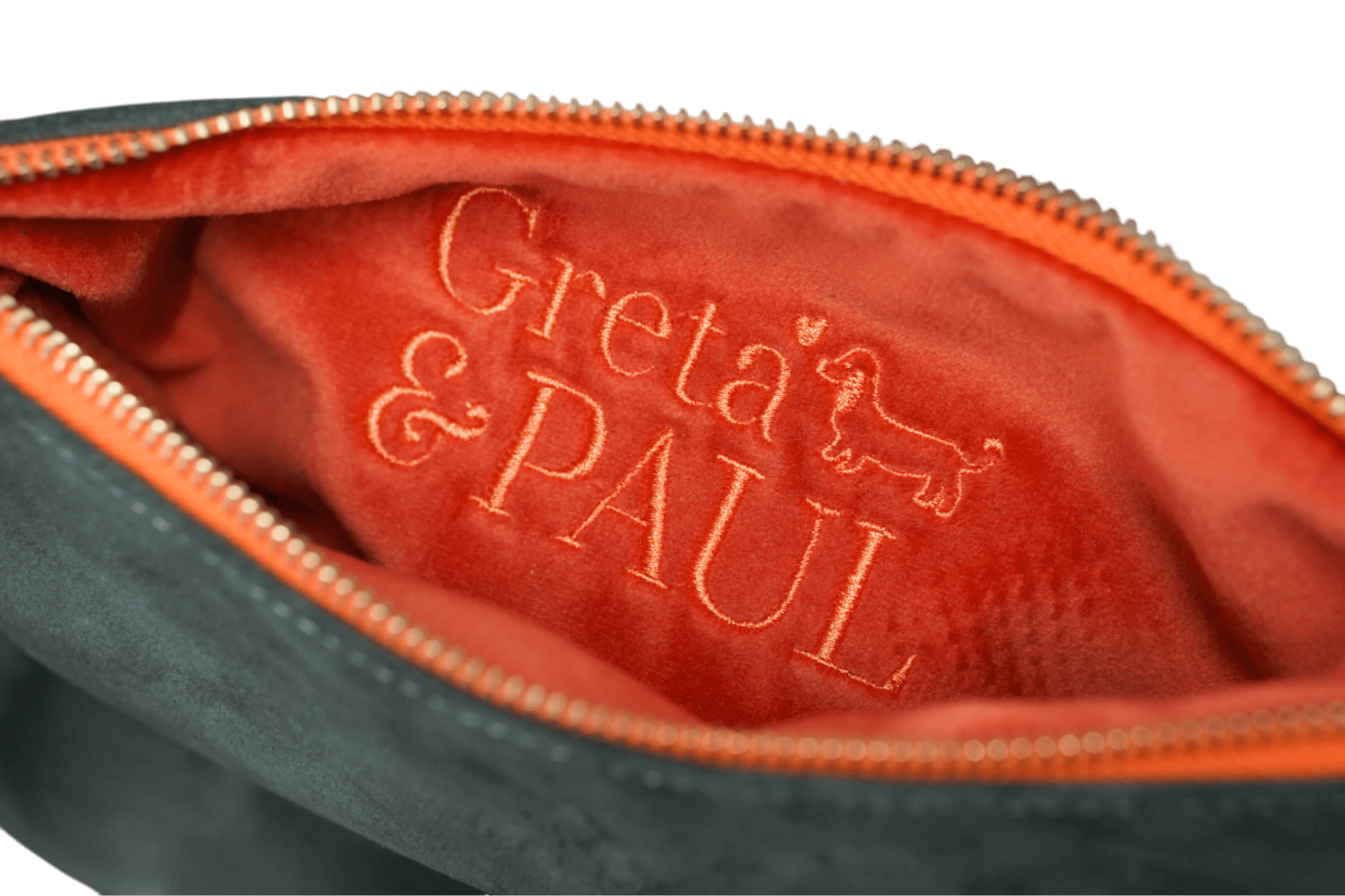 Detailaufnahme des orangefarbenen Innenfutters der Khaki Greta & PAUL Clutch 'Stella Deluxe' mit aufwendig gesticktem Logo