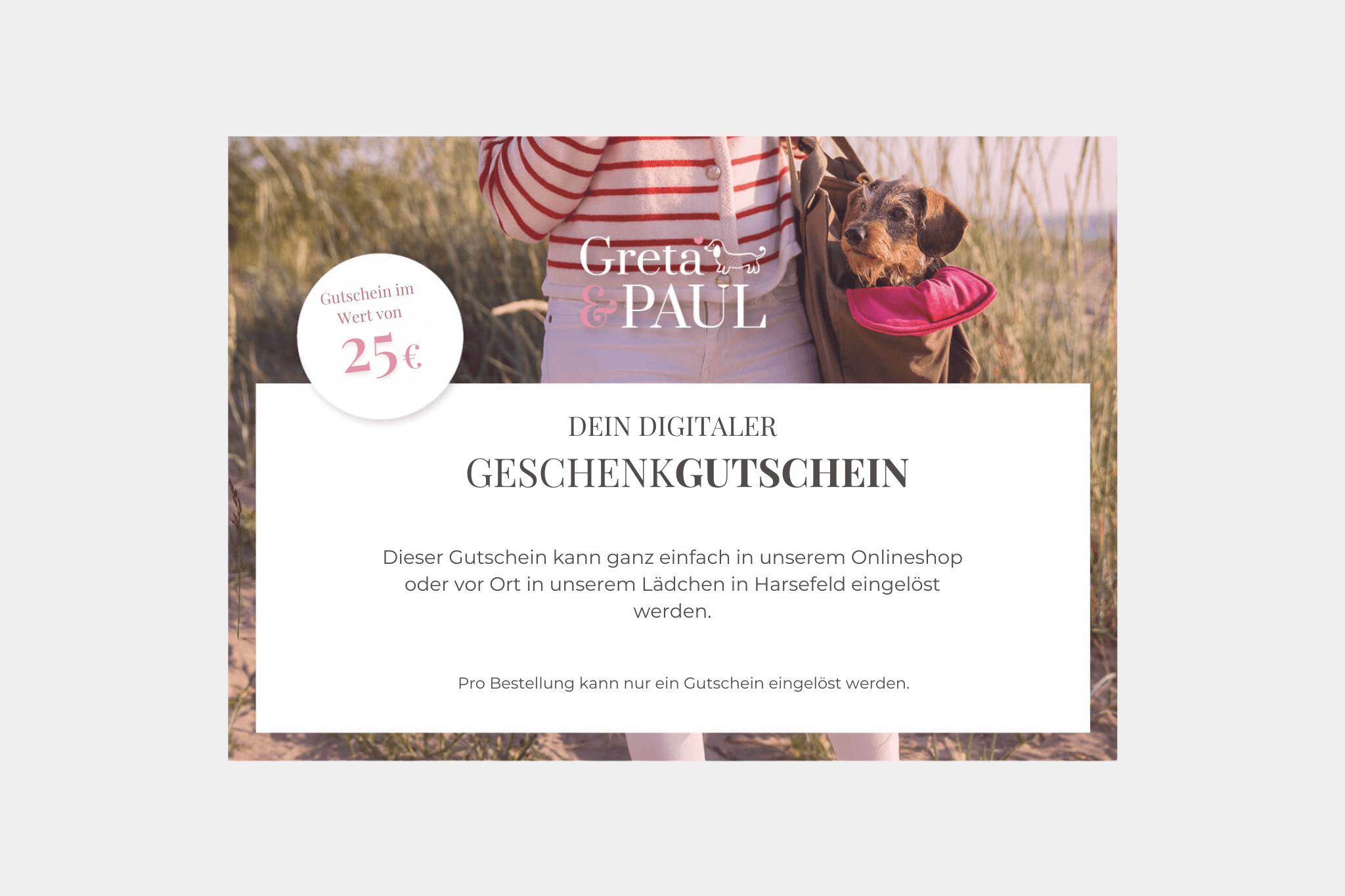 Digitaler Geschenkgutschein von Greta & Paul über 25 Euro für Hundezubehör. Im Hintergrund ist ein Dackel in einer Hundetragetasche zu sehen, der am Strand getragen wird. Ideal als Geschenk für Hundebesitzer.