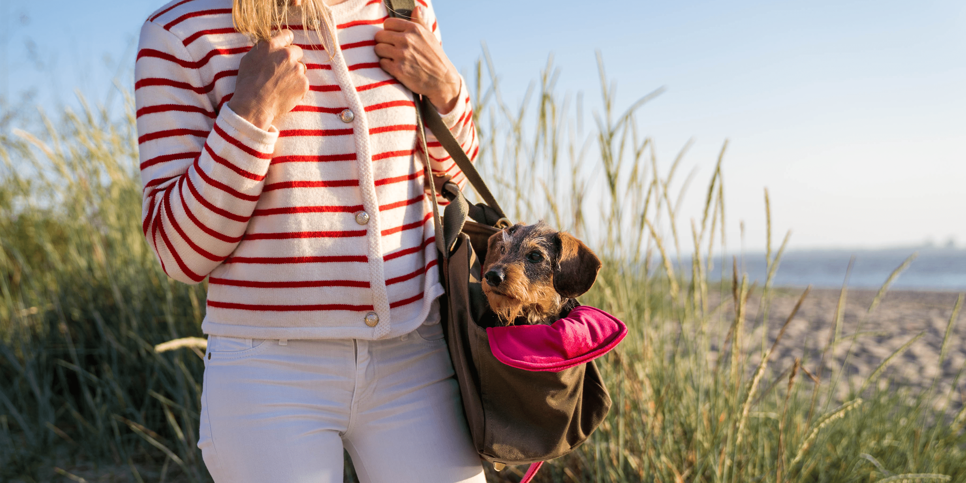Julia mit Dackel Greta in Premium-Hundetasche von Greta & PAUL am Strand.