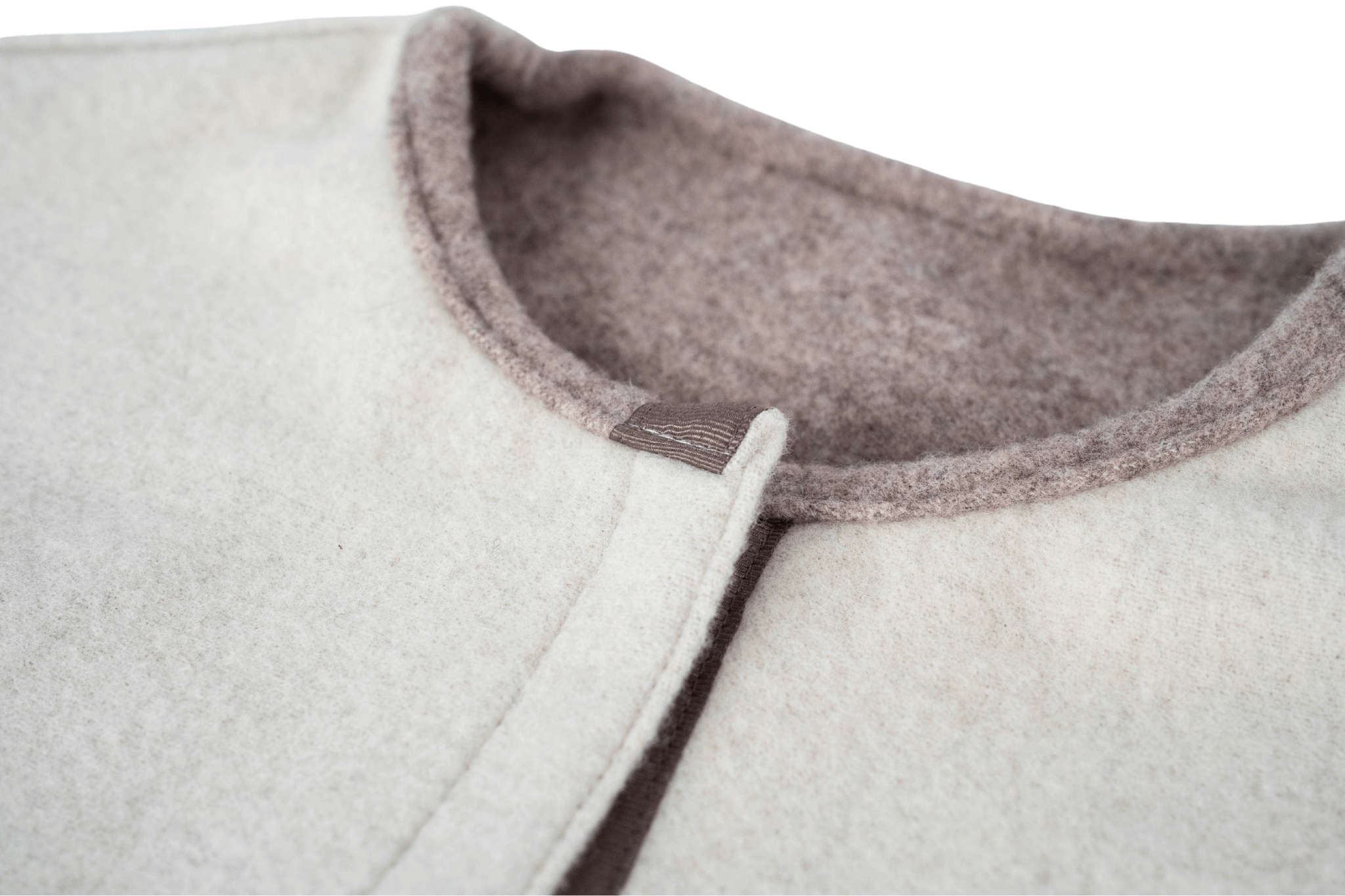 Detailaufnahme des Halsausschnitts des Wendecapes Gretchen Couture in Beige-WollweiĂ.