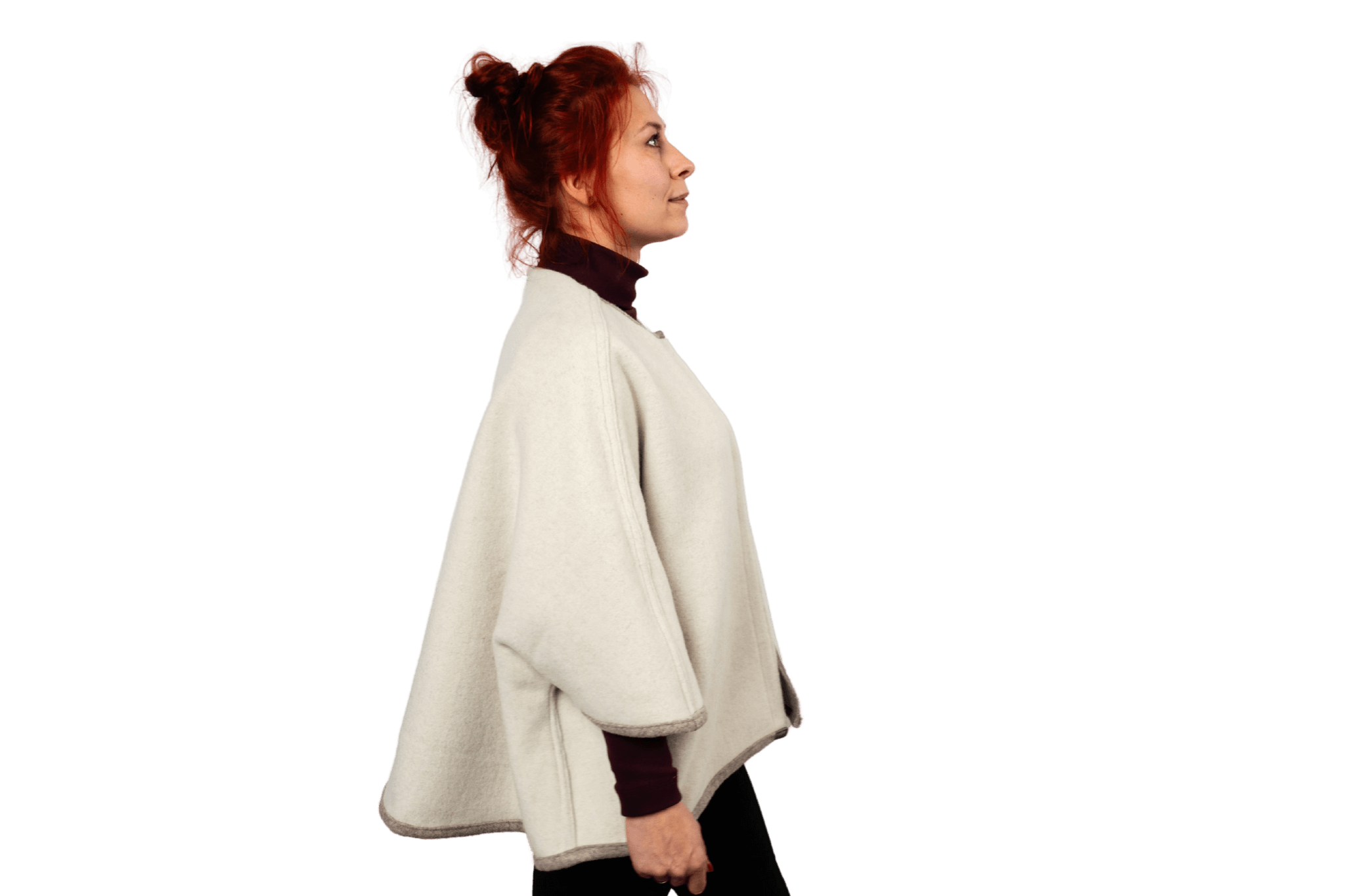 Model prĂ€sentiert das Wendecape Gretchen Couture von Greta & PAUL in Beige-WollweiĂ, Seitenansicht der gewendeten wollweiĂen Seite.