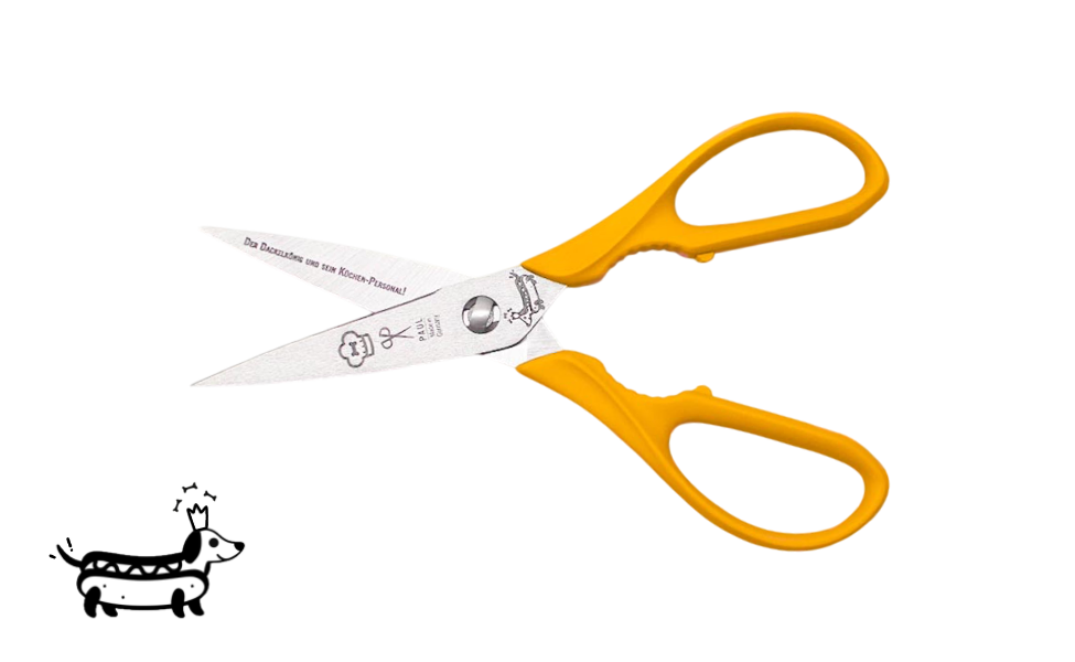 Greta's Dackel-Küchenschere von PAUL in Dunkelgelb mit Aushebefunktion und Gravur "Der Dackelkönig und sein Küchen-Personal!".

