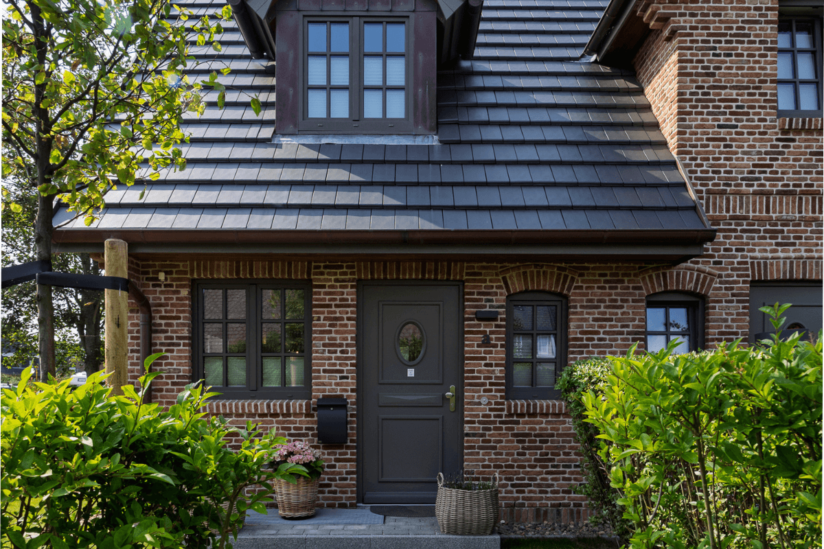 Außenansicht der Ferienwohnung 'Greta & Sylt': ein charmantes Backsteinhaus mit idyllischem Eingangsbereich.
