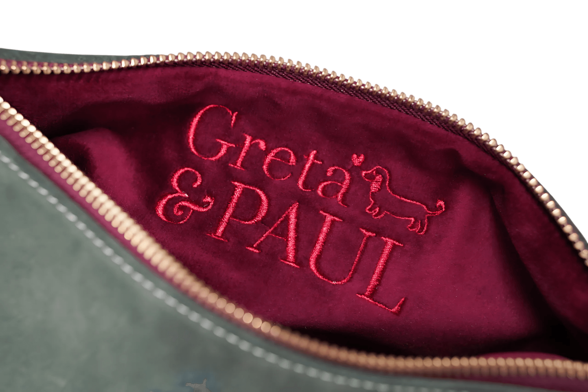 Detailaufnahme des very berry-farbenen Innenfutters der Khaki Greta & PAUL Clutch 'Stella Deluxe' mit aufwendig gesticktem Logo