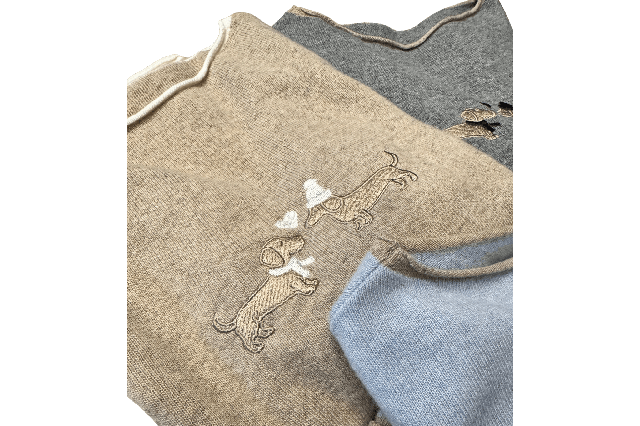 Drei zusammengelegte Gretas Dackelpullover in Beige, Grau und Hellblau -  Detailaufnahme von Bestickung und Kragen